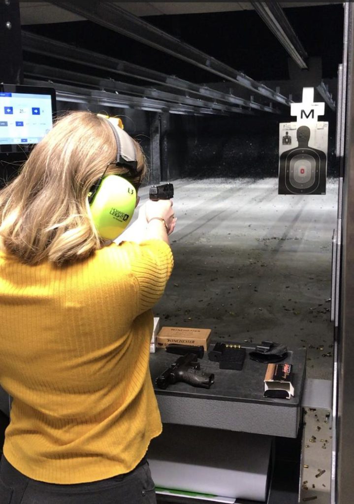 Female student training shooting her pistol at the indoor shooting range.